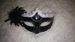 Black mask with silver glitter lining and a black feather on the left side.