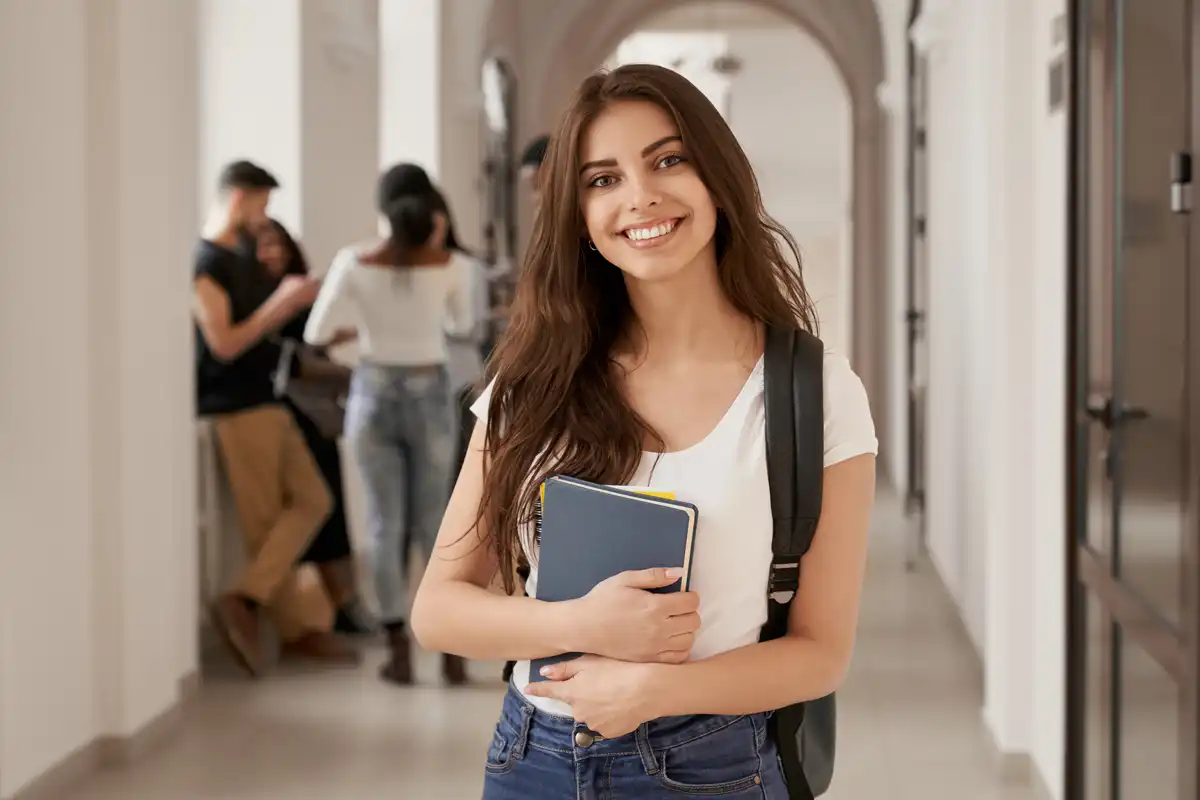 Girl standing in hallway smiling.